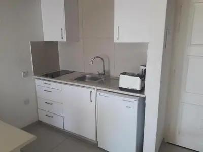 a small white kitchen with a sink and a counter at Boronia Hotel Apartments in Larnaka