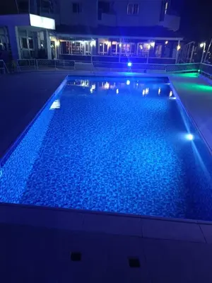 a large swimming pool with blue water at night at Boronia Hotel Apartments in Larnaka