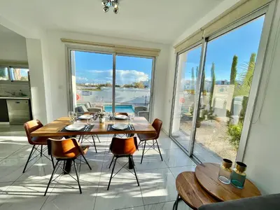 a dining room with a table and chairs and a large window at Alasia Villa ll Kapparis in Paralimni
