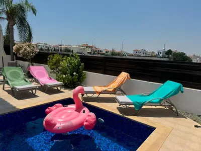 a pool with chairs and a pink flamingo on a balcony at Villa TaMalDi side sea view - new renovated! in Paralimni