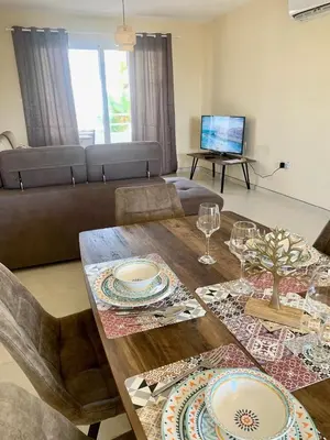 a living room with a wooden table with plates on it at Nissi 3 E8 Pool View Apt in Ayia Napa