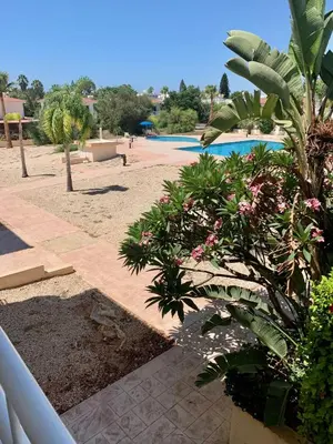 a view of a swimming pool with trees and plants at Nissi 3 E8 Pool View Apt in Ayia Napa