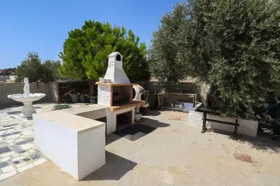 a stone grill in a courtyard with a tree at Captivating 2-Bed House in Alaminos