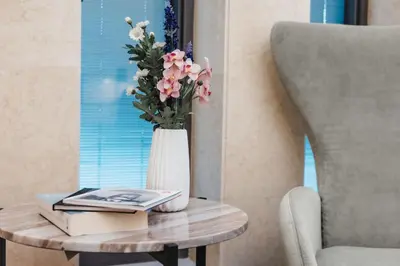 a vase with flowers on a table next to a chair at 16 EXECUTIVE SUITES in Nicosia