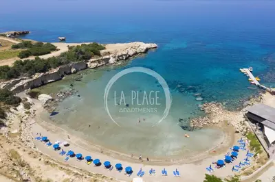 an aerial view of a beach with umbrellas and the ocean at Cozy 2 Bedroom Family Apartment w/ Pool in Protaras