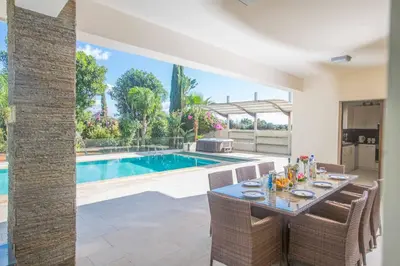 a dining room with a table and a swimming pool at Protaras Demetra Villa DE1 in Protaras