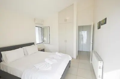 a white bedroom with a large bed with white sheets at Serifos Villa 7 - 100 meters from Malama Beach in Protaras