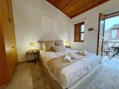 a bedroom with a large bed with white sheets and pillows at Maison Damianou Elegant Loft in Omodos