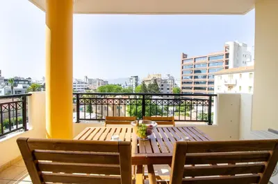 a wooden table and chairs on a balcony with a view at Flat in Nicosia's centre in Nicosia