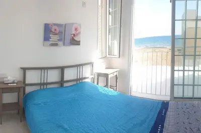 a bedroom with a blue bed and a view of the ocean at Sea Heart Villa Beachfront in Pyla