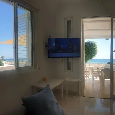 a living room with a tv and a view of the ocean at Sea Heart Villa Beachfront in Pyla