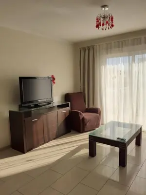 a living room with a tv and a chair and a coffee table at Luxury Cozy Apartment near NISSI BEACH in Ayia Napa