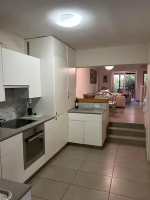 a kitchen with white cabinets and a living room at Beautiful maisonette in Protaras in Protaras