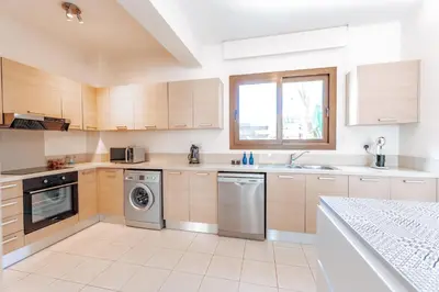 a kitchen with wooden cabinets and a washer and dryer at WealthyStays Sunset Villa, 3min walk to Sea in Paralimni
