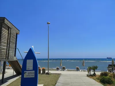 a blue sign on a beach with the ocean at Miranda Beach House in Voroklini