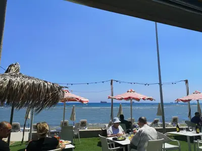 a group of people sitting at tables on the beach at Miranda Beach House in Voroklini