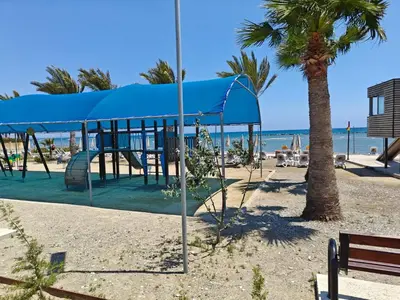 a playground on the beach with a blue canopy at Miranda Beach House in Voroklini
