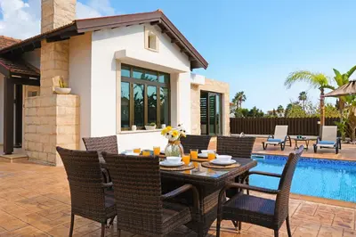 a patio with a table and chairs next to a pool at Villa Lara - 3bed Bangalow with Large Pool in Ayia Napa