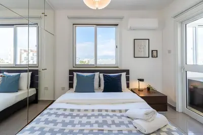 a bedroom with a large bed with blue and white pillows at Jayde 2-Bedroom Apartment in Larnaca in Larnaka