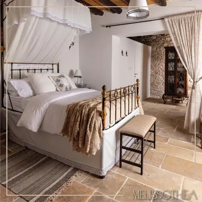 a bedroom with a large bed and a chair at Melissothea Stone Suites in Mesana