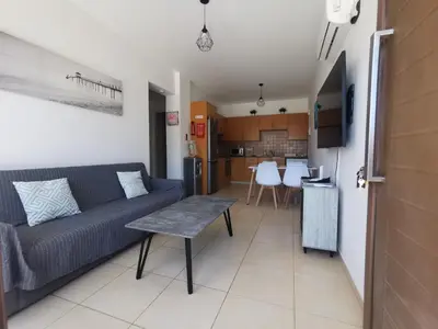 a living room with a couch and a kitchen at Sunny coast apartment by the sea in Protaras