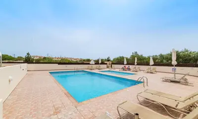 a large swimming pool with chairs and a swimming poolvisor at Estelle Suite in Ayia Napa