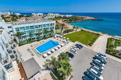 an aerial view of a resort with a pool and a parking lot at Austin - Coralli Beachfront Apartment in Protaras