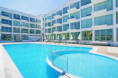 a large swimming pool in front of a building at Austin - Coralli Beachfront Apartment in Protaras
