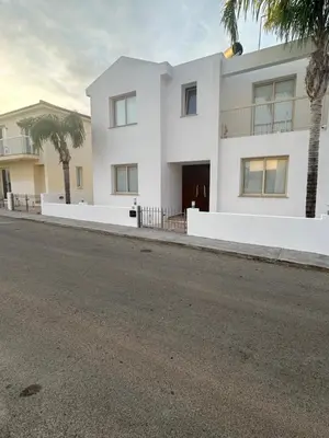 a white house with palm trees in front of it at DAFNI VILLA BY PANN in Protaras