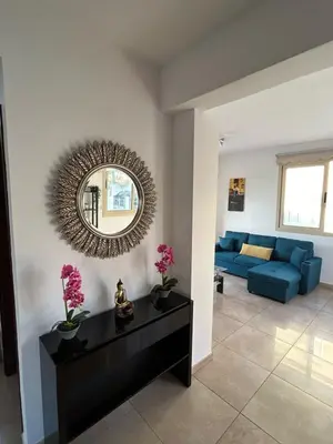 a living room with a blue couch and a mirror at DAFNI VILLA BY PANN in Protaras