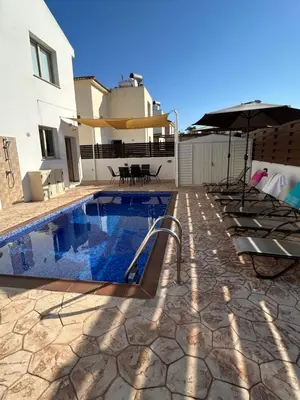 a swimming pool with an umbrella next to a house at DAFNI VILLA BY PANN in Protaras