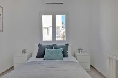 a white bedroom with a large bed with blue pillows at Phaedrus Living: Luxury Residence Faneromeni in Larnaka