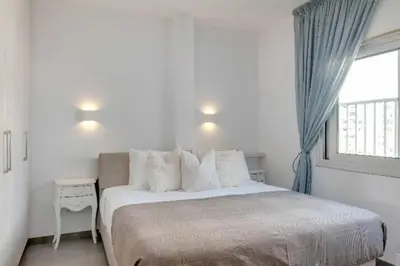 a bedroom with a bed with pillows and a window at Phaedrus Living: Beach Front Flat Kyma in Limassol