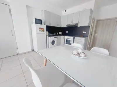 a white kitchen with a white table and chairs at One bedroom city centre in Larnaka