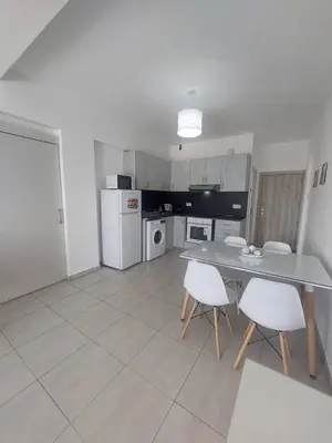 a kitchen with a table and white chairs in it at One bedroom city centre in Larnaka