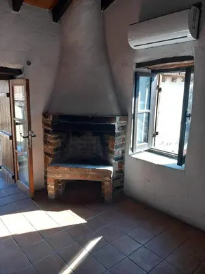 a brick fireplace in a room with two windows at Πετροκτιστο in Kakopetria