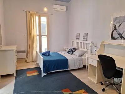 a bedroom with a bed and a desk and a window at Pavlos Place - Blue Haven in Limassol