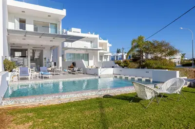 a villa with a swimming pool in front of a house at Protaras Elaia Luxury Seafront Villa in Protaras