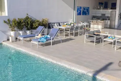 a swimming pool with chairs and a table and a swimming pool at Protaras Elaia Luxury Seafront Villa in Protaras