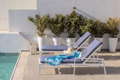 a pair of blue lounge chairs next to a pool at Protaras Elaia Luxury Seafront Villa in Protaras