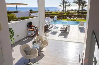 a patio with chairs and a swimming pool at Protaras Elaia Luxury Seafront Villa in Protaras