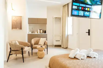 a room with a bed and chairs and a tv at The Secret Yard in Larnaka