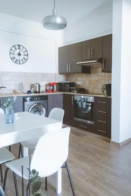 a kitchen with a white table and white chairs at Blue Touch Pervolia Paradise near the beach in Larnaka