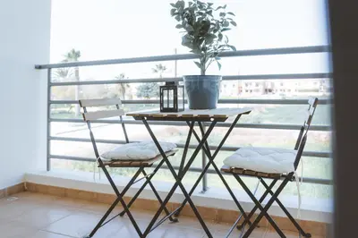 a table with two chairs and a plant on a window at Blue Touch Pervolia Paradise near the beach in Larnaka