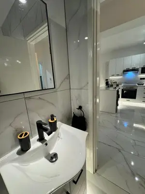 a white bathroom with a sink and a mirror at Spacious 1 bedroom flat in Foinikoudes! in Larnaka