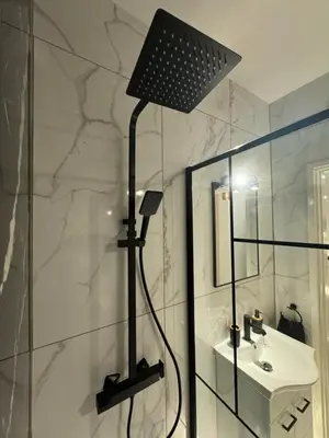 a bathroom with a shower with a sink and a lamp at Spacious 1 bedroom flat in Foinikoudes! in Larnaka