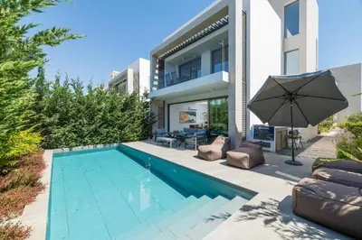 a swimming pool with an umbrella next to a house at Azure Seaview - Ruby Villa in Protaras