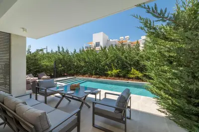 a patio with a table and chairs next to a swimming pool at Azure Seaview - Ruby Villa in Protaras