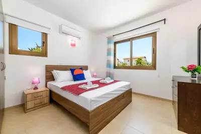a bedroom with a bed and two windows at Kymma Villa #12 in Ayia Napa