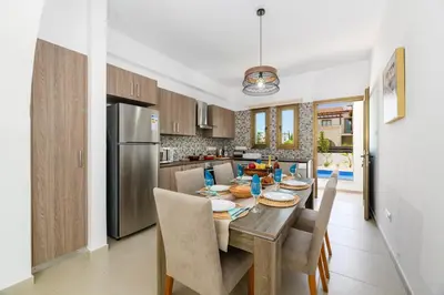 a kitchen with a table with chairs and a refrigerator at Kymma Villa #5 in Ayia Napa